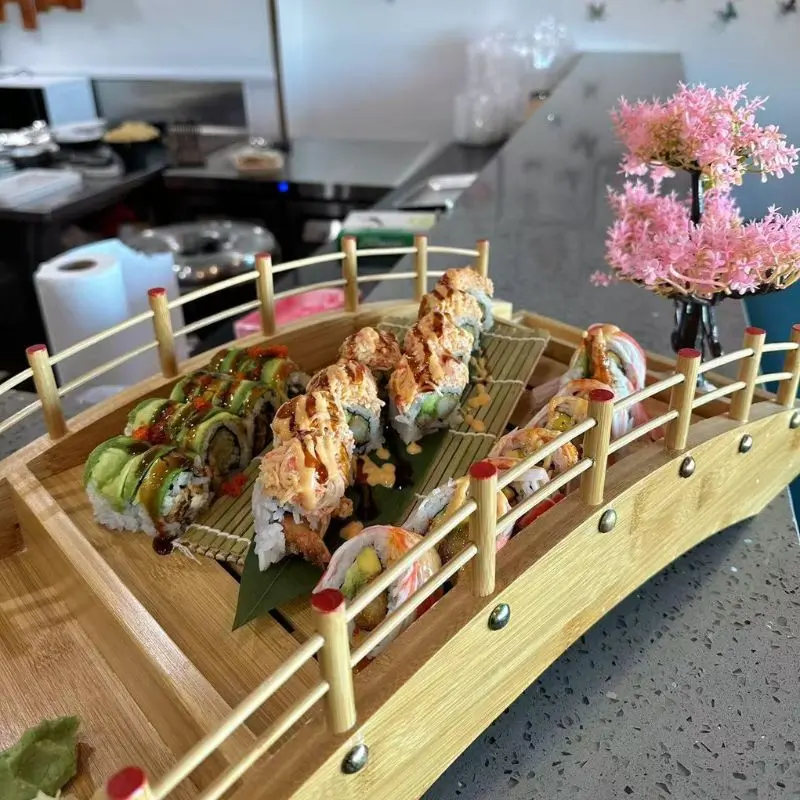Sushi rolls placed on a bridge - shaped wooden tray, nicely decorated.