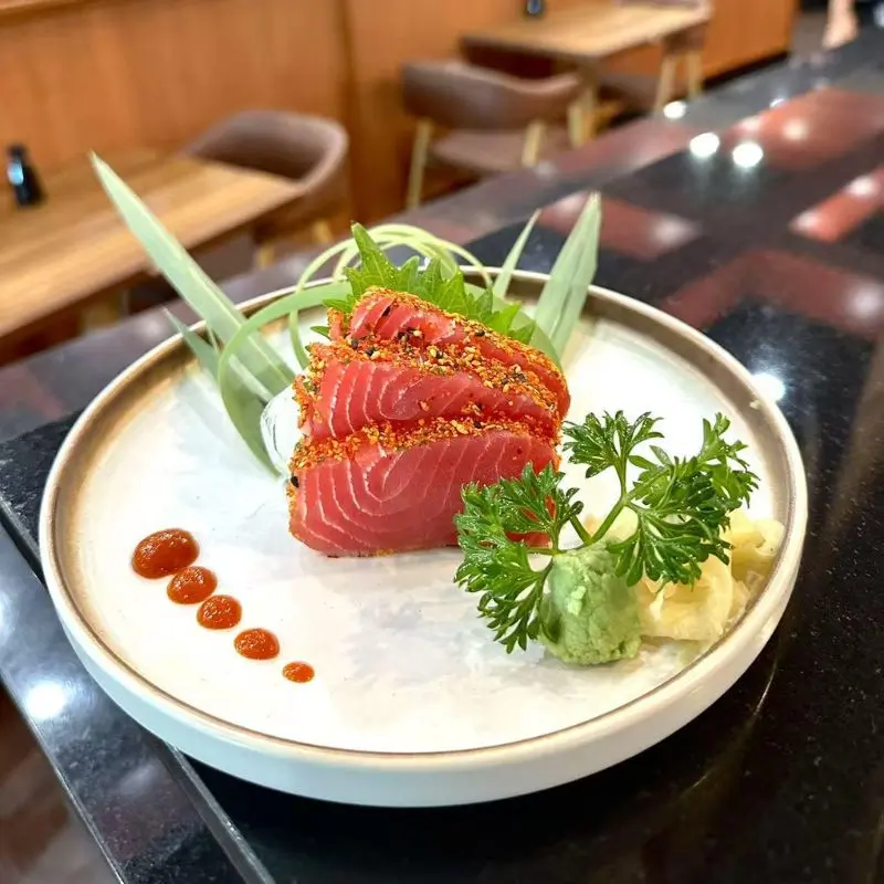 Spiced tuna sashimi, garnished with greens and wasabi.